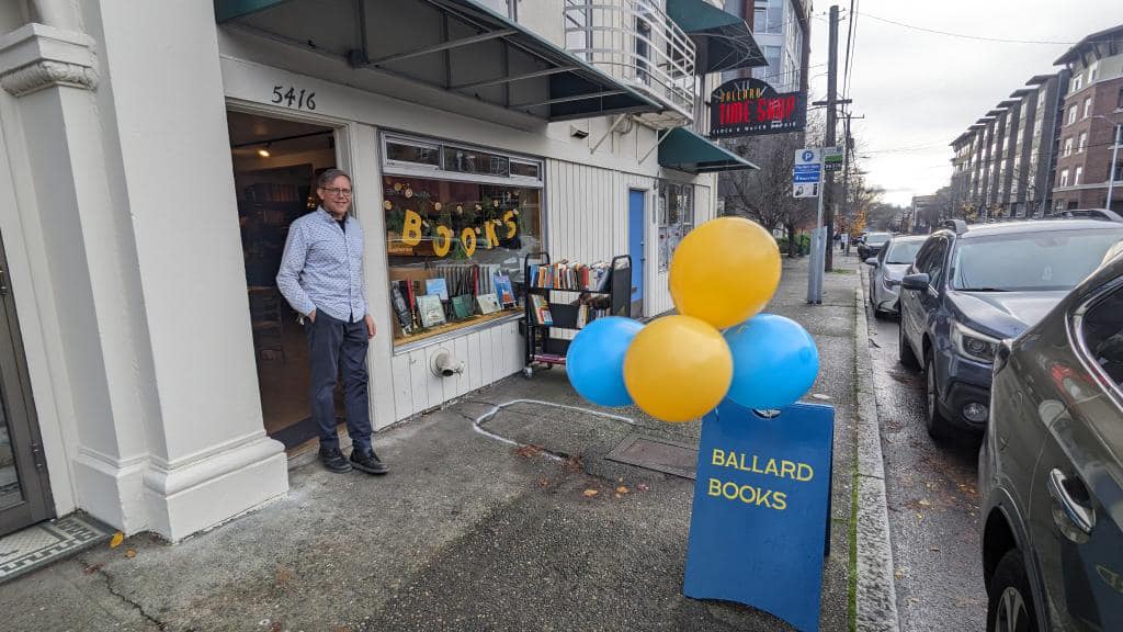 A man stands in front of a bookstore.