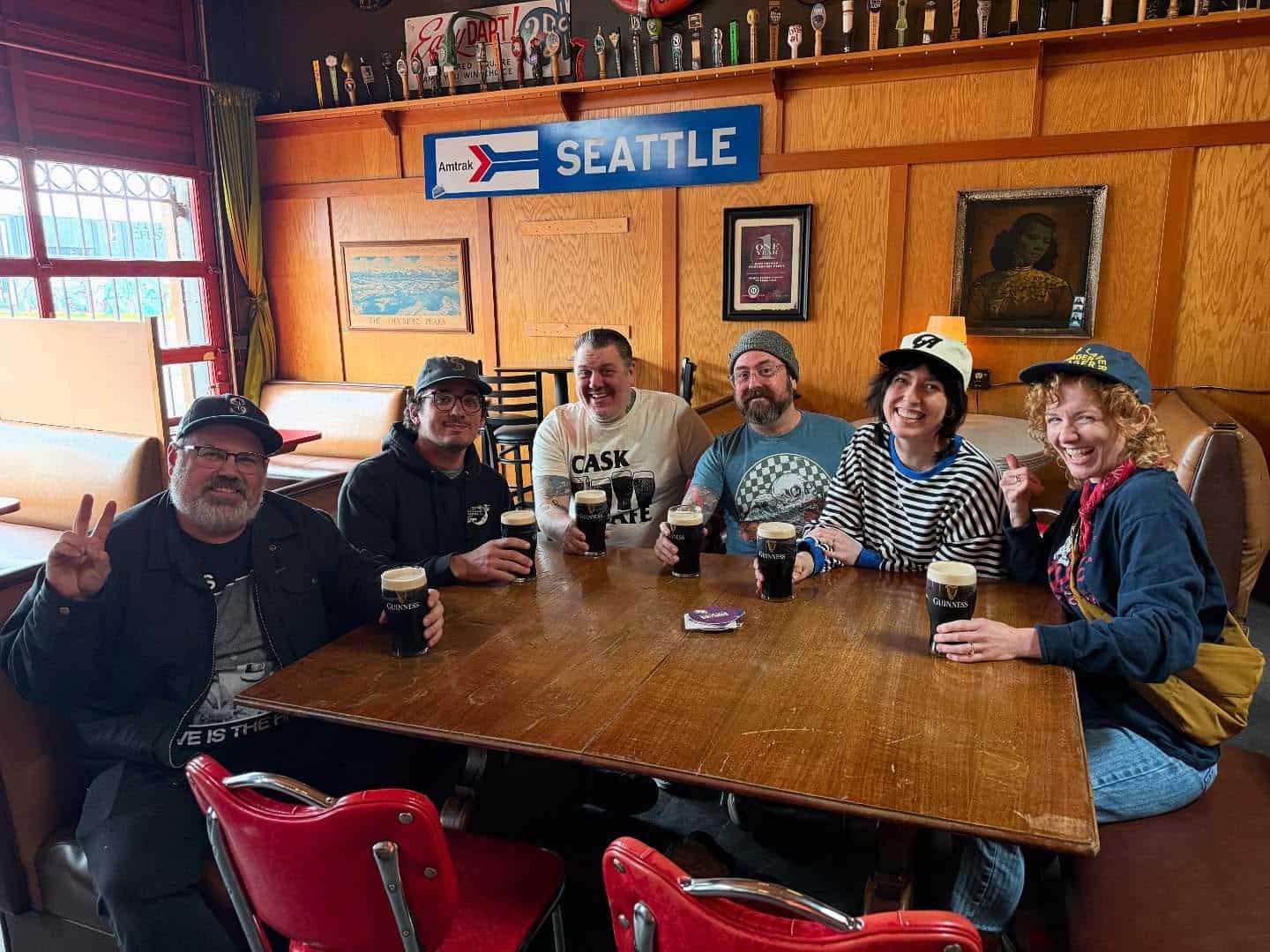 A group of people sit around a table drinking beer.