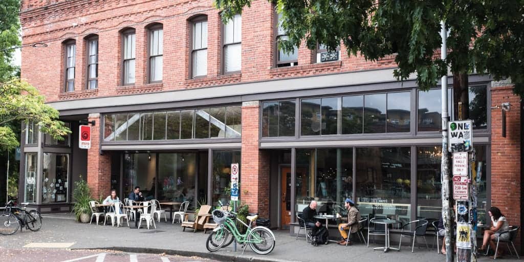 A brick building with a cafe and chairs.