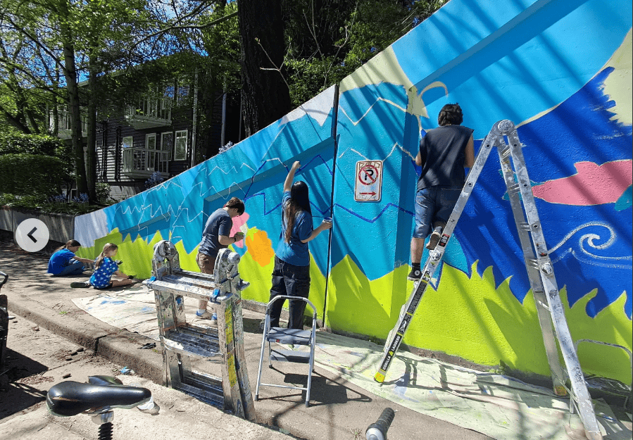 A group of painters work on a colorful mural.