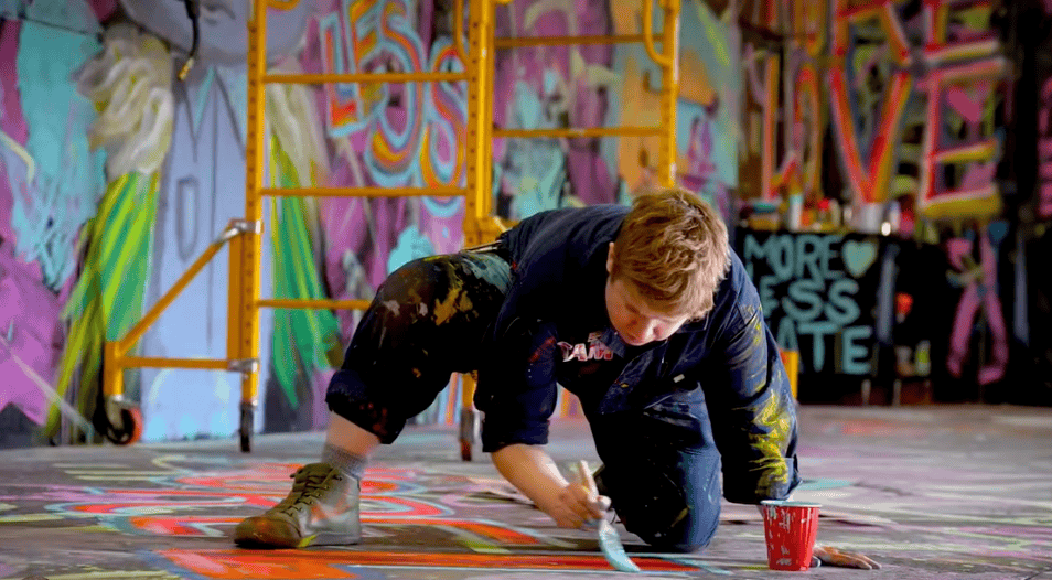 A person paints a mural on the floor of a building.